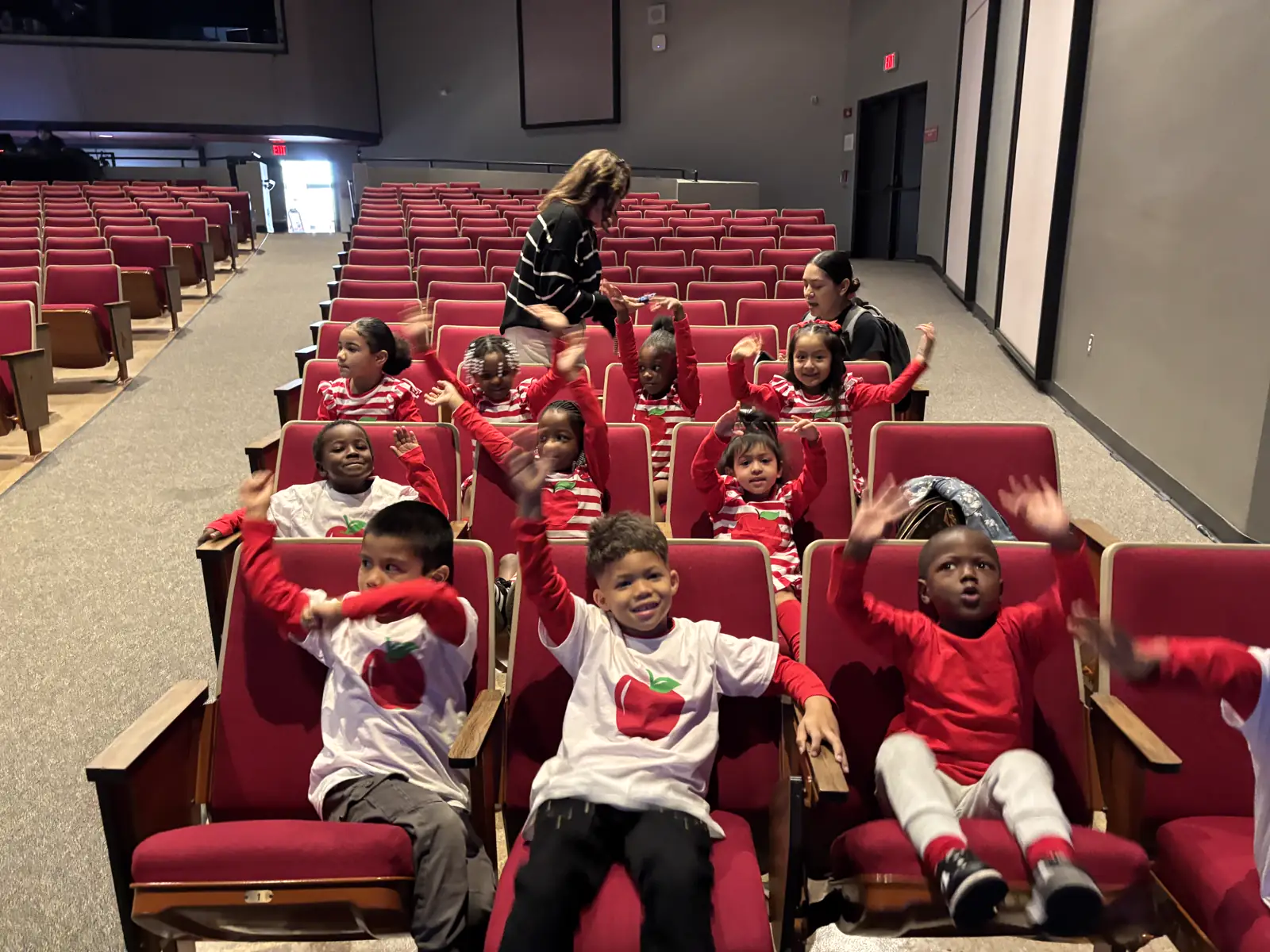Appleseed children raising their hands with joy during a performance outing