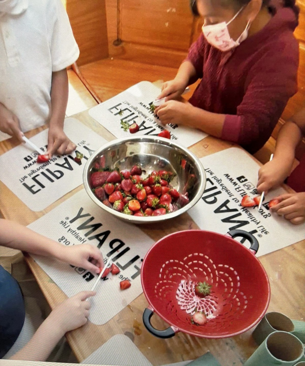Children preparing fresh strawberries together at a culinary arts table